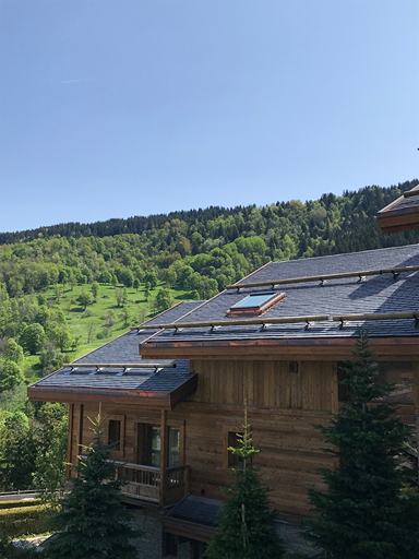 Chalet de madera en los Alpes franceses con tejado de pizarra natural sobre el valle
