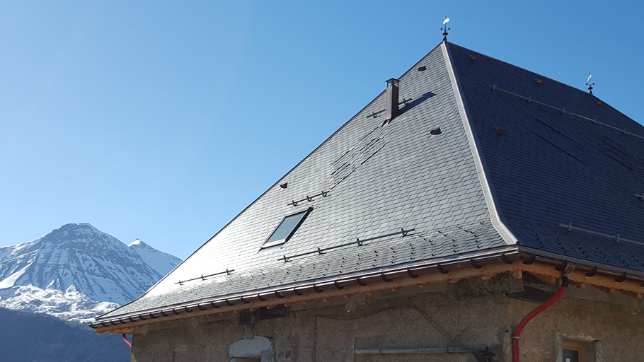 Chalet en los Alpes franceses con cubierta de pizarra natural y montañas nevadas al fondo
