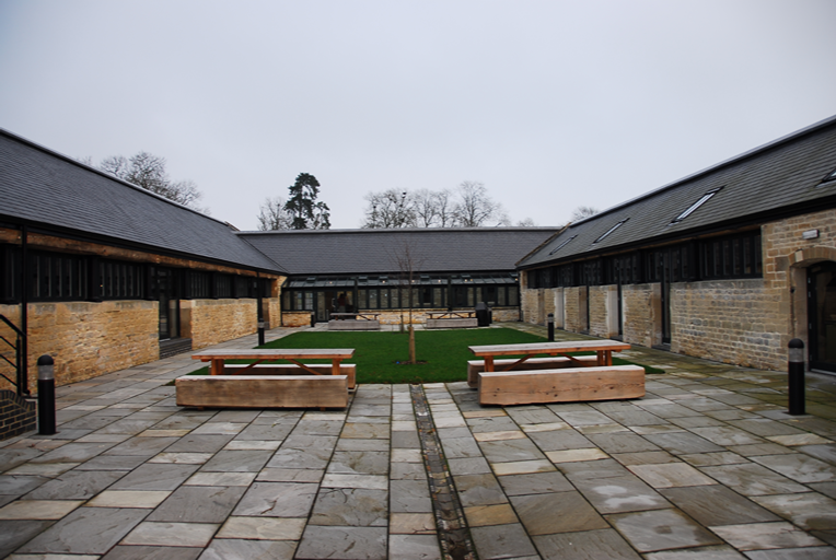 Patio empedrado de Blenheim Palace, Oxfordshire, rodeado de edificios con cubierta de pizarra natural