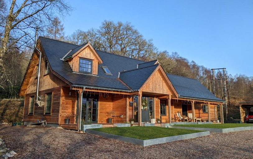 Fachada de madera y cubierta de pizarra natural con buhardillas en una vivienda escocesa