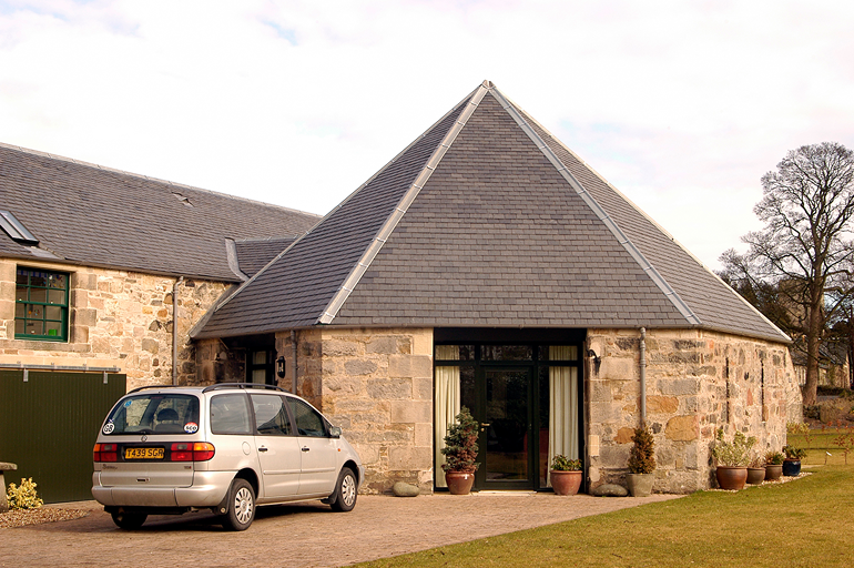Edificio de piedra en Dalmeny Steading, Escocia, con cubierta a cuatro aguas de pizarra natural