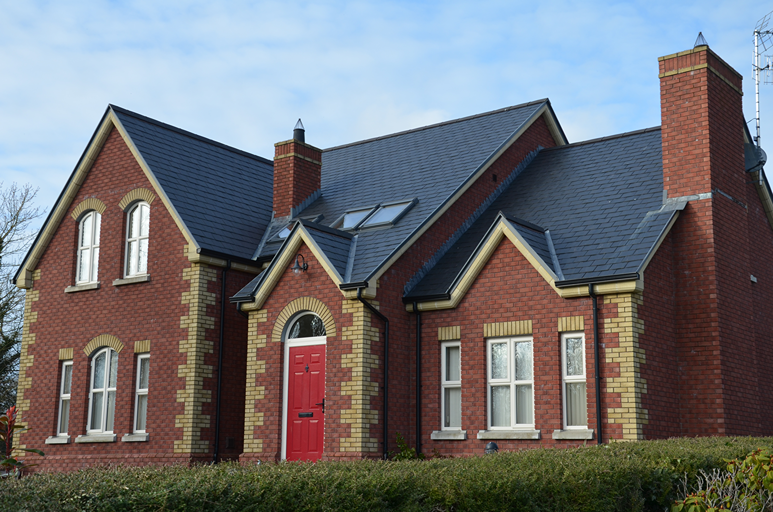 Vivienda en Irlanda con puerta roja, fachada de ladrillo y cubierta de pizarra natural