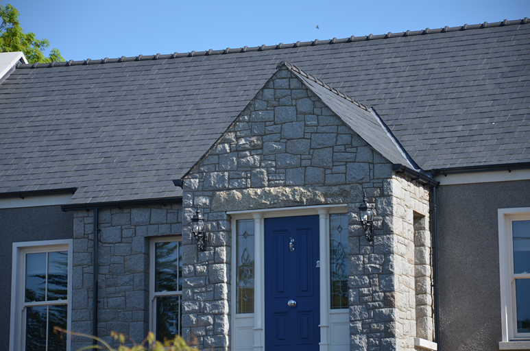 Casa en Irlanda con fachada de piedra, puerta azul y cubierta de pizarra natural