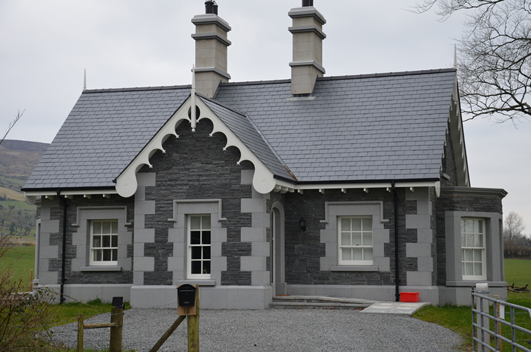 Casa señorial de piedra gris en Irlanda con cubierta de pizarra natural y aleros decorados