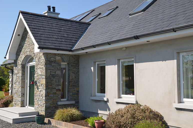 Cubierta de pizarra natural con claraboyas en una vivienda de fachada blanca en Irlanda