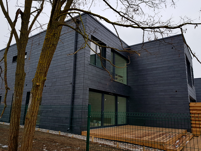 Vivienda unifamiliar en Lituania con revestimiento de fachada en pizarra natural y terraza de madera